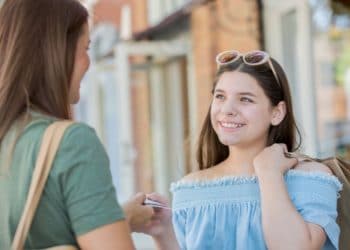 Mother giving credit card with money to daughter