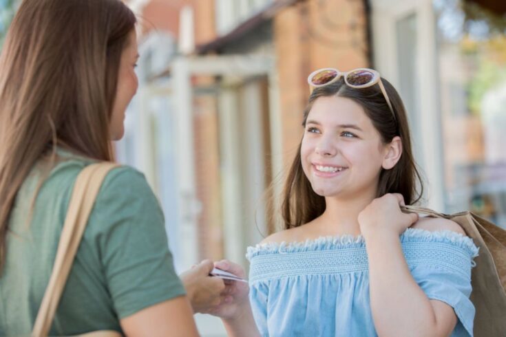 Mother giving credit card with money to daughter