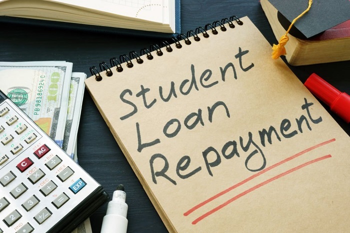 Student loan repayment sign, notepads, calculator and cash.