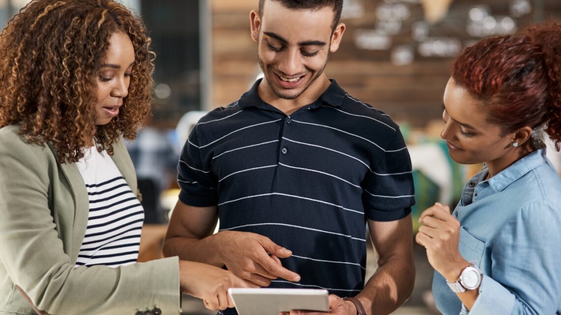 Employers value internships as young professionals collaborate and review work on a tablet in a real workplace setting