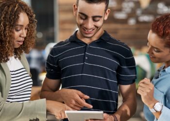 Employers value internships as young professionals collaborate and review work on a tablet in a real workplace setting