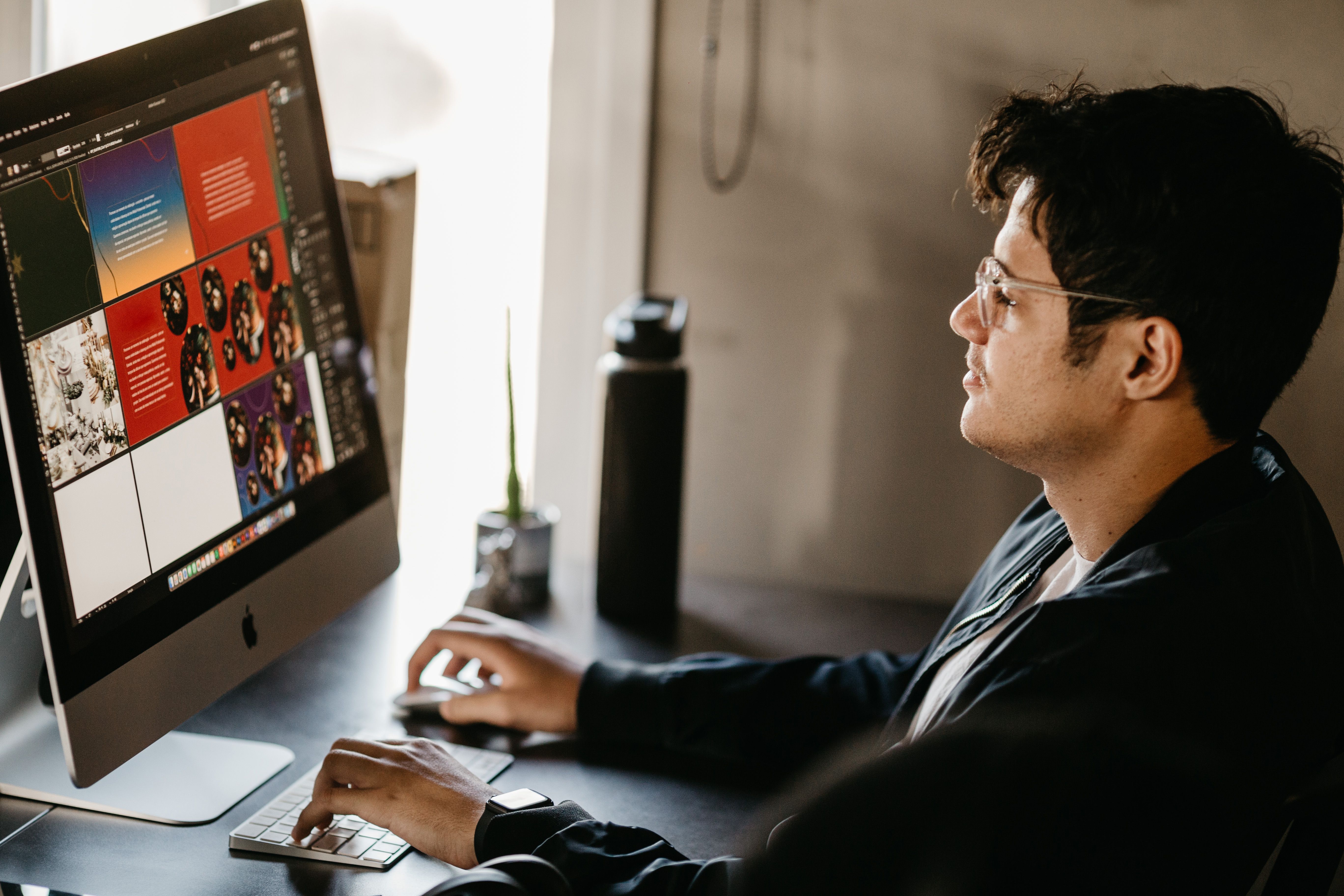 Graphic designer working on a computer in a modern office with creative visuals on screen