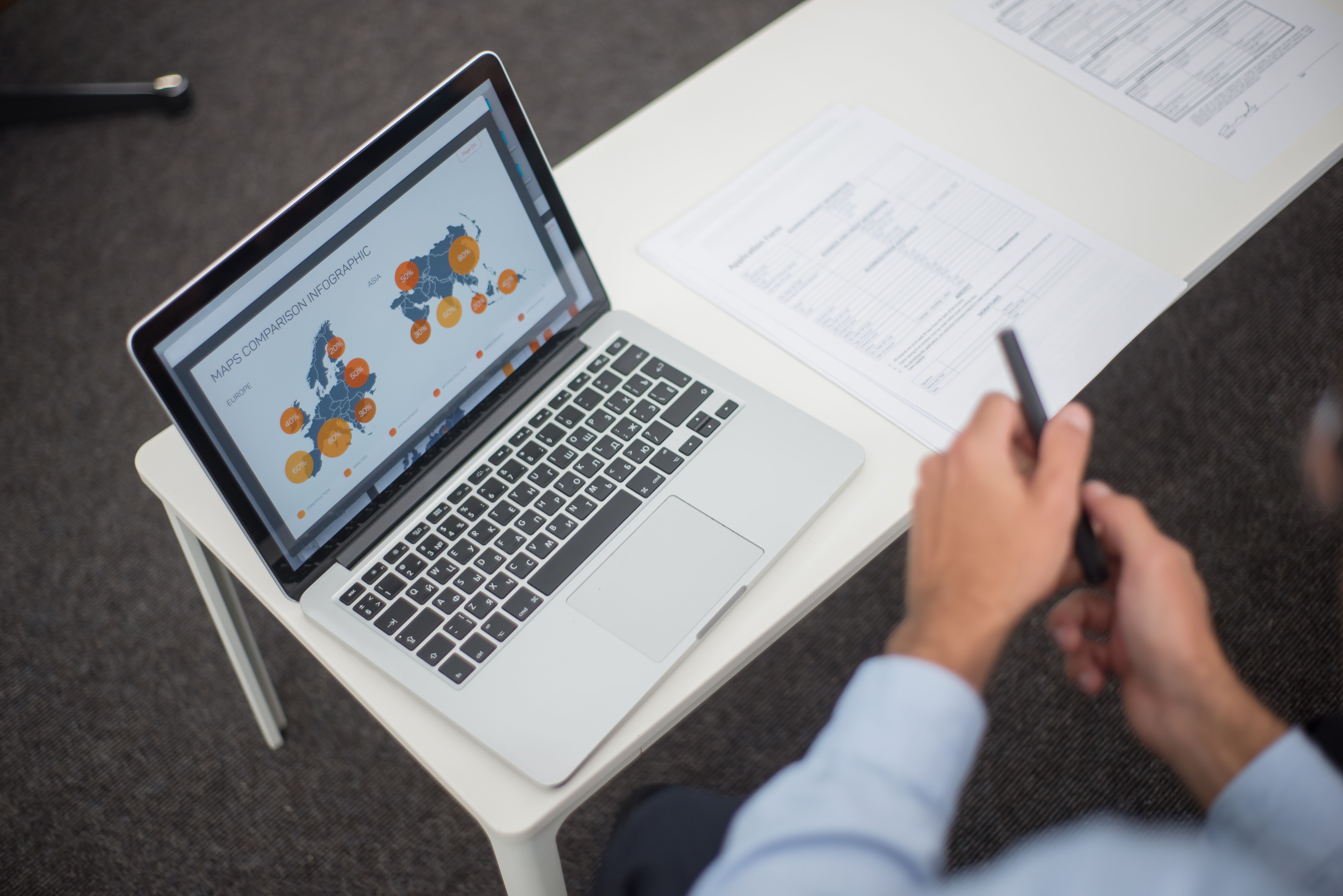 Professional analyzing data infographics on a laptop at an office desk