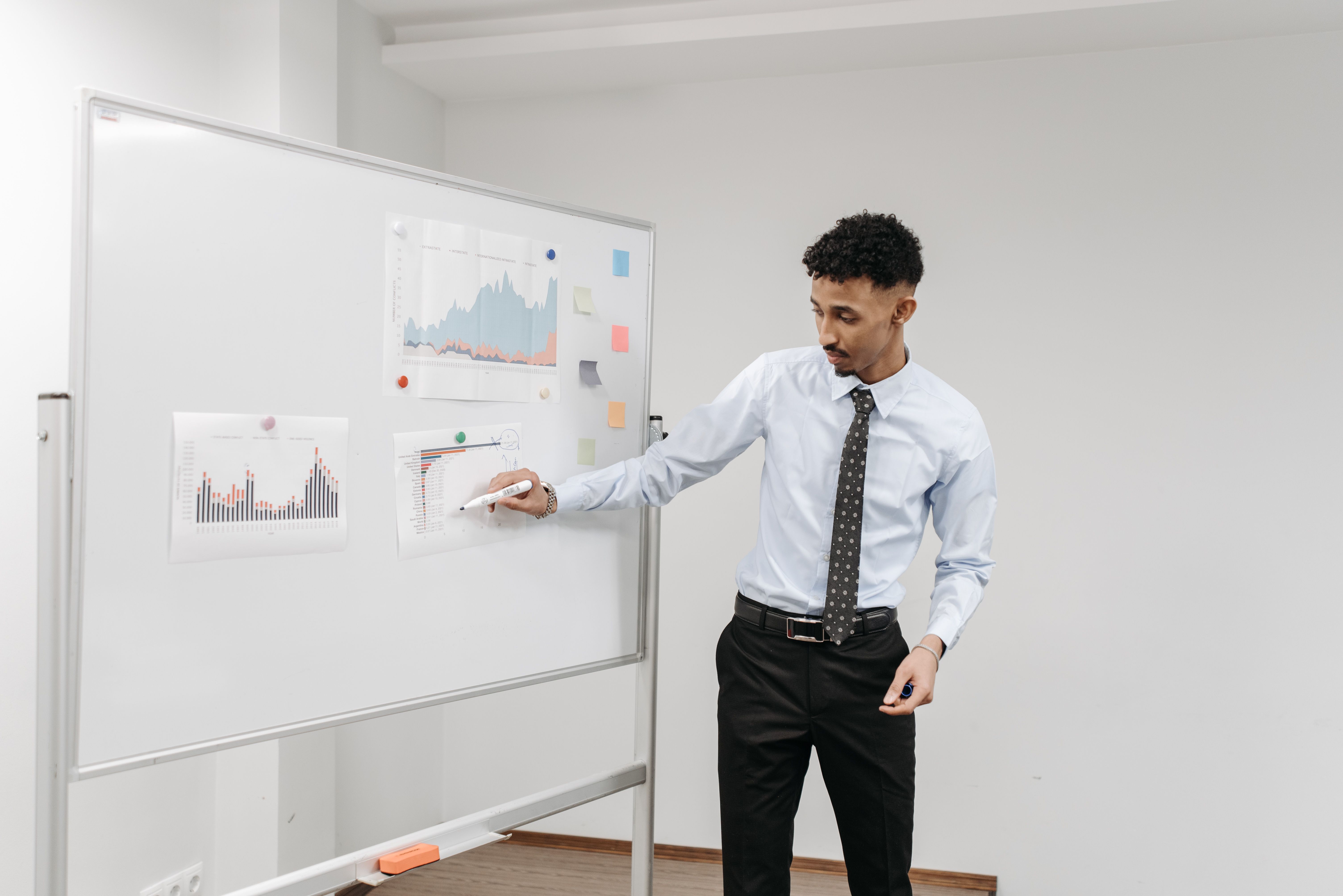 Professional presenting charts on a whiteboard during a collaborative office meeting